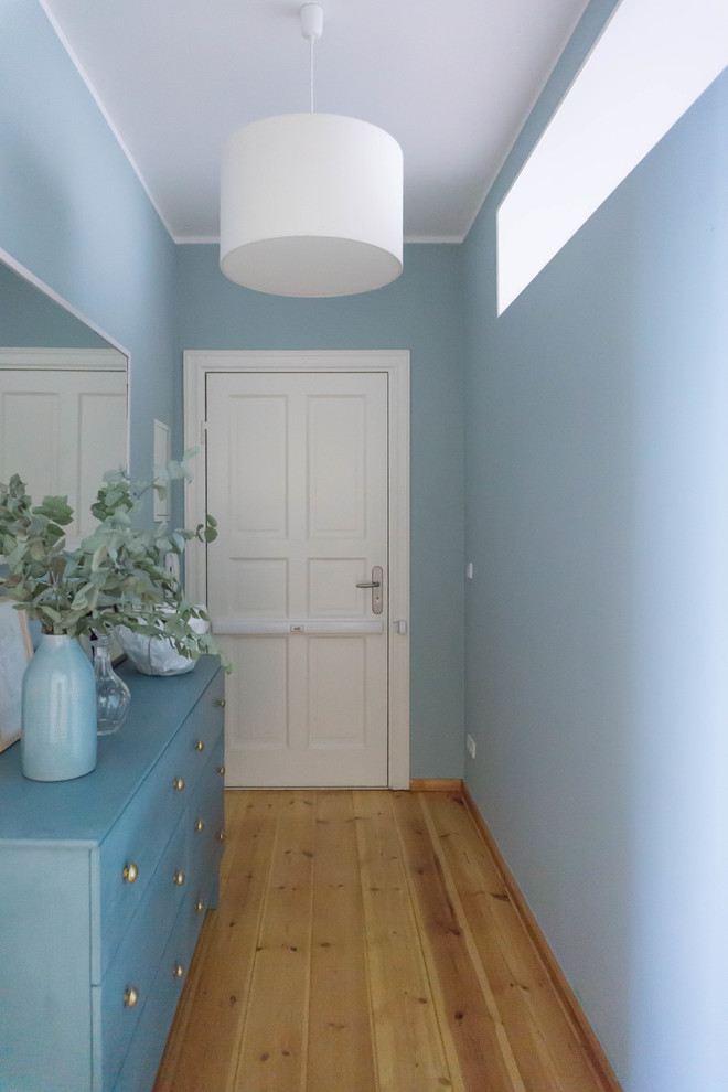 Example of a trendy light wood floor and beige floor hallway design in Other with blue walls