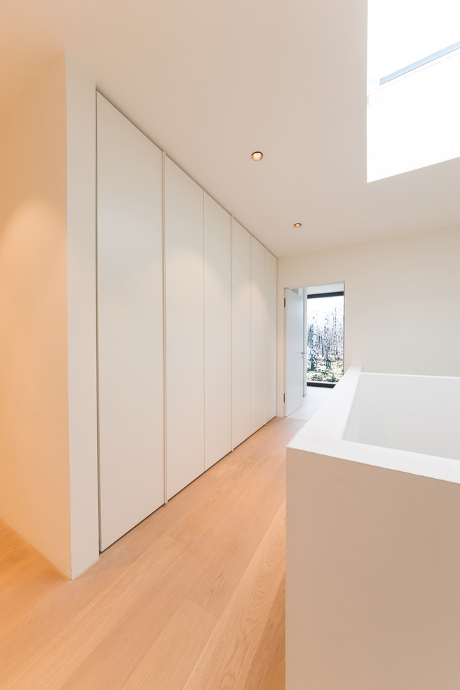Mittelgroßer Moderner Flur mit weißer Wandfarbe, braunem Holzboden und braunem Boden in Sonstige