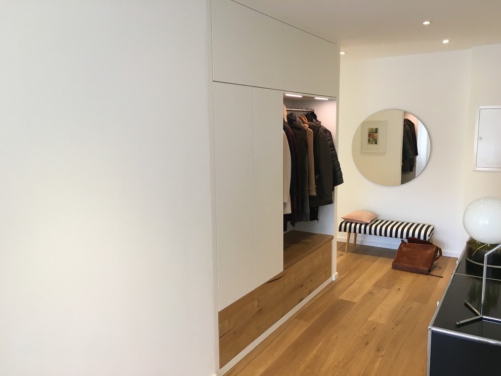 Стильный дизайн: большой коридор в современном стиле с белыми стенами, деревянным полом и коричневым полом - последний тренд