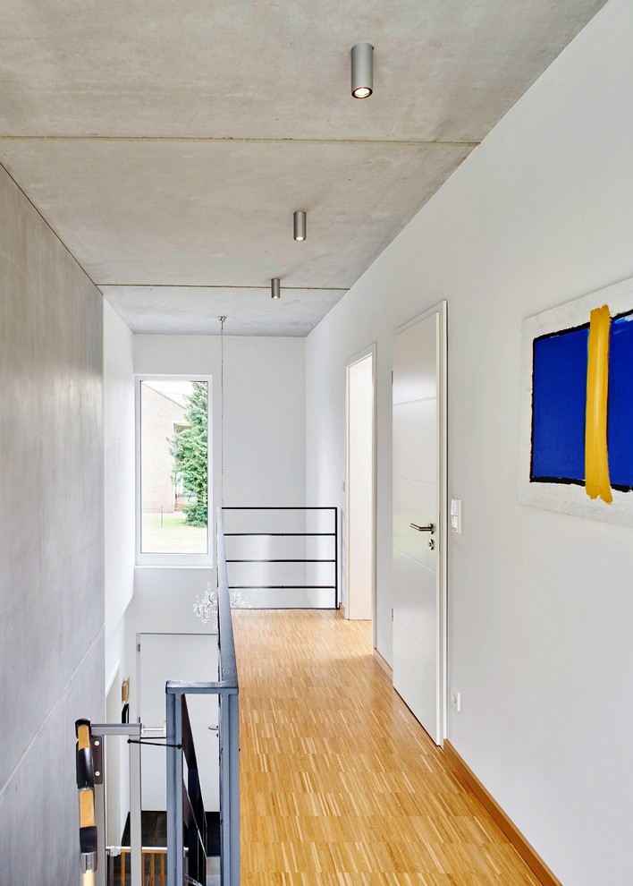 Réalisation d'un couloir design de taille moyenne avec un mur blanc, parquet clair et un sol beige.