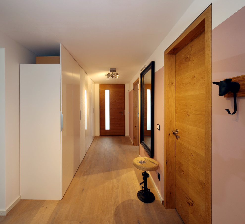 Esempio di un ingresso o corridoio design di medie dimensioni con parquet chiaro, pareti rosa e pavimento marrone