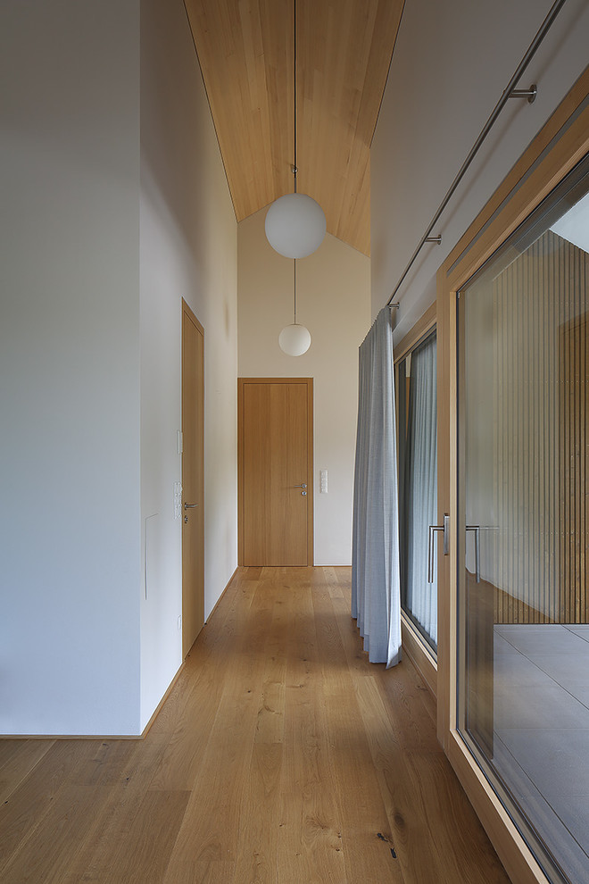 На фото: коридор среднего размера в современном стиле с белыми стенами и паркетным полом среднего тона