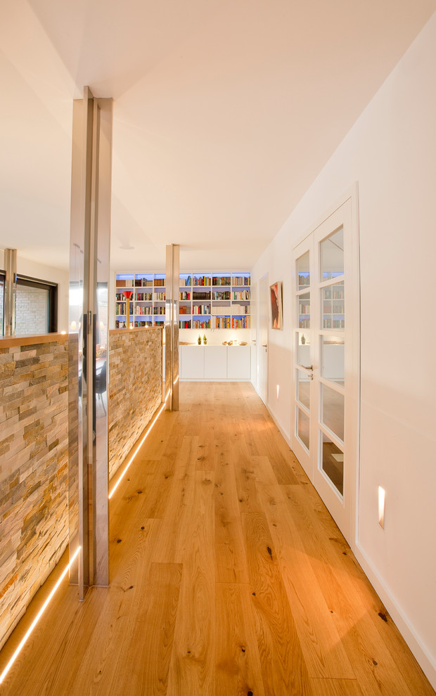 Idées déco pour un grand couloir contemporain avec un mur blanc et un sol en bois brun.