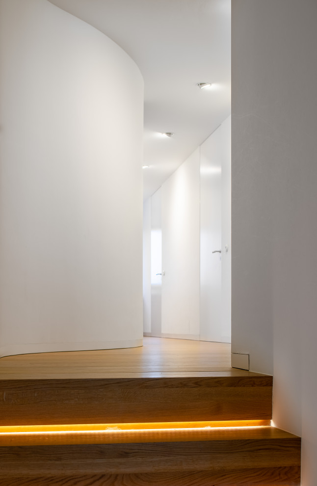 Geräumiger Moderner Flur mit weißer Wandfarbe, braunem Holzboden und braunem Boden in Sonstige