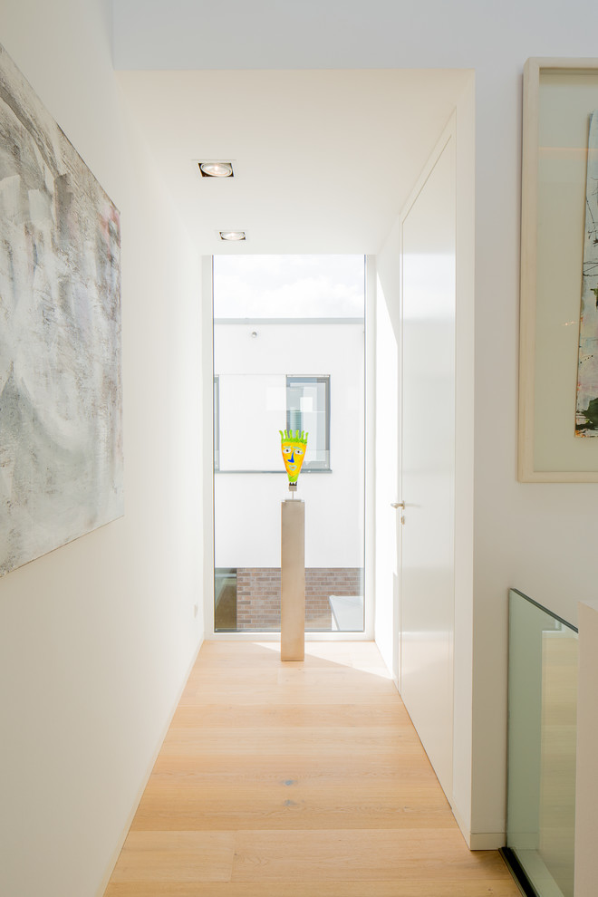 Foto di un piccolo ingresso o corridoio moderno con pareti bianche, pavimento in legno massello medio e pavimento beige