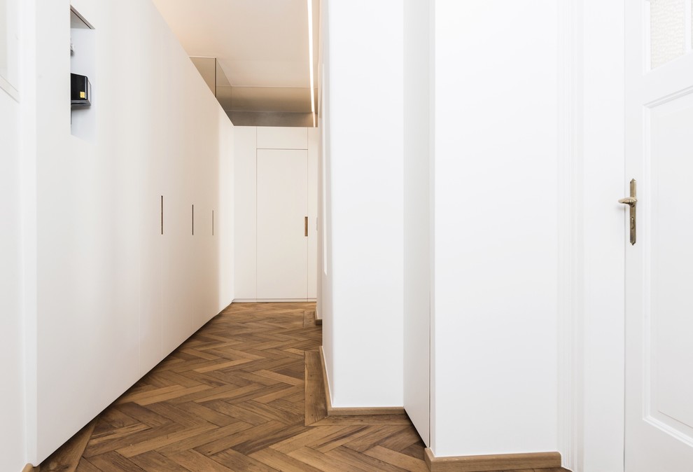 Imagen de recibidores y pasillos modernos de tamaño medio con paredes blancas, suelo de madera en tonos medios y suelo marrón
