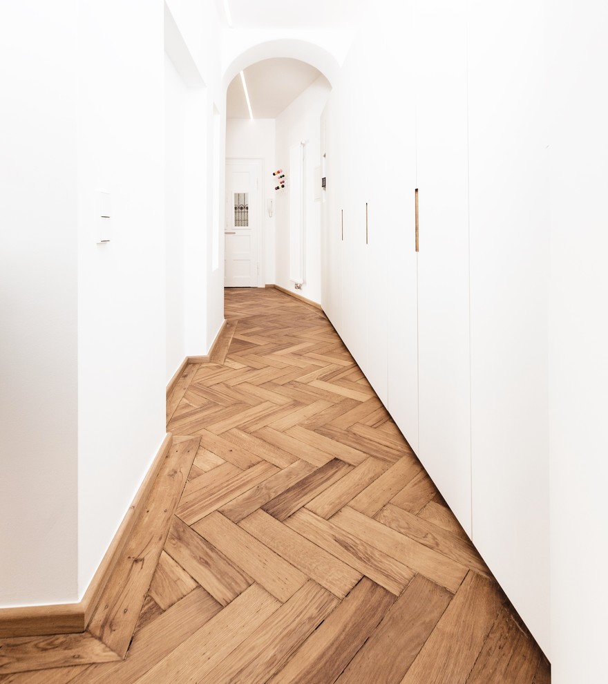 Imagen de recibidores y pasillos minimalistas de tamaño medio con paredes blancas, suelo de madera en tonos medios y suelo marrón