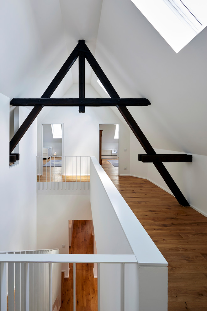 Großer Moderner Flur mit weißer Wandfarbe, braunem Holzboden und braunem Boden in Köln