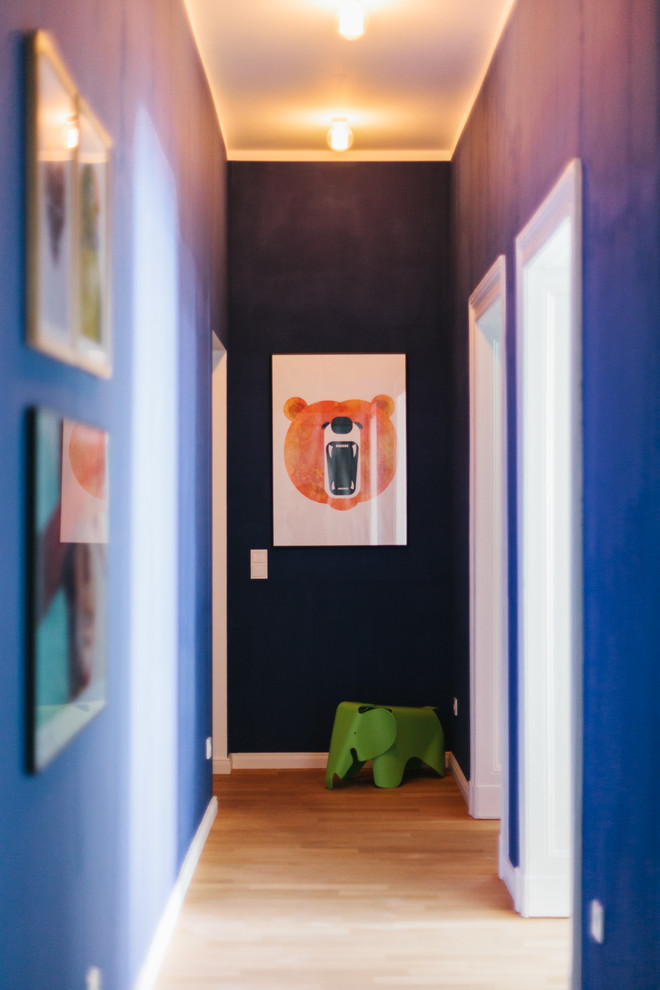 Ejemplo de recibidores y pasillos bohemios pequeños con paredes azules y suelo de madera clara