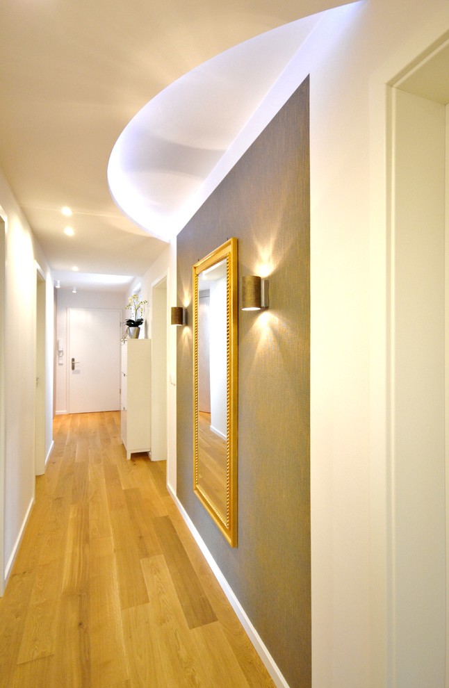 Idée de décoration pour un couloir design de taille moyenne avec un sol en bois brun et un mur blanc.