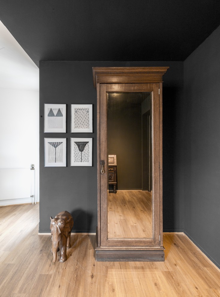 Example of a small island style medium tone wood floor and brown floor hallway design in Hamburg with black walls