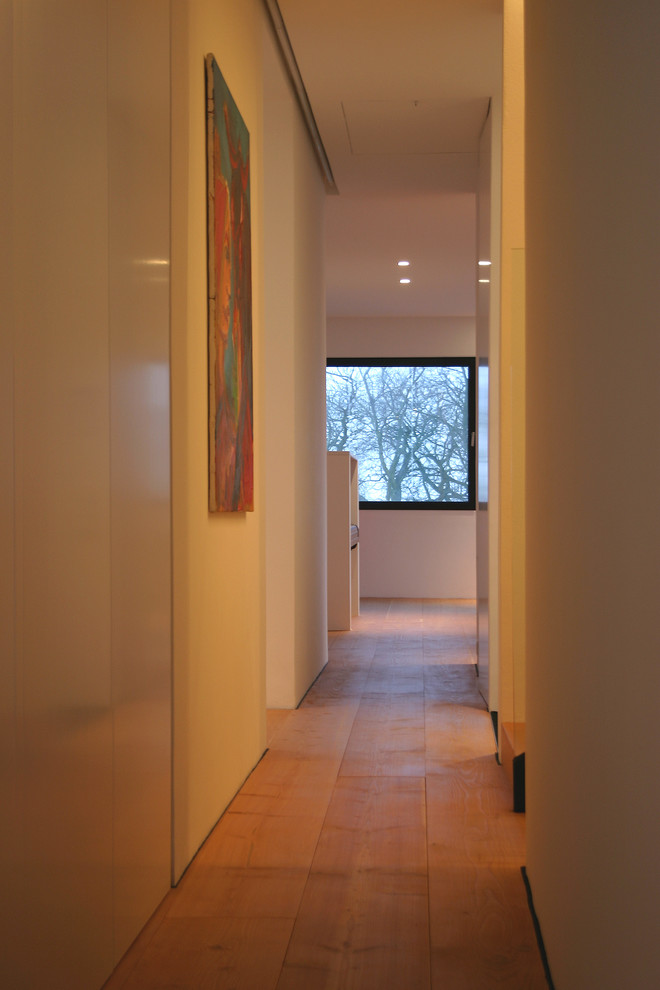 Geräumiger Moderner Flur mit weißer Wandfarbe, dunklem Holzboden und beigem Boden in Hannover