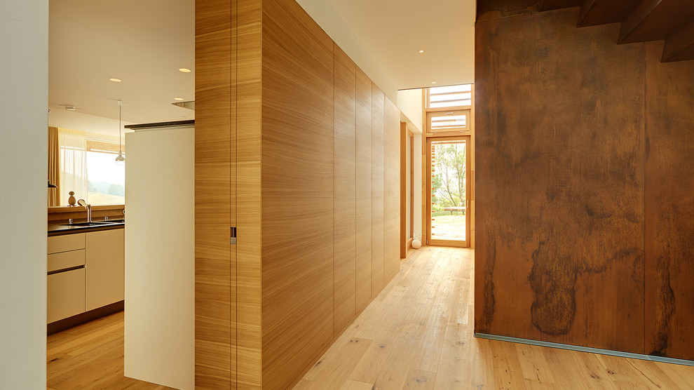 Inspiration pour un couloir design de taille moyenne avec un mur marron et parquet clair.