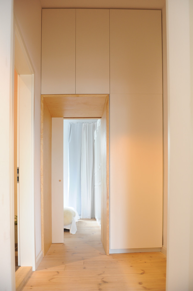 Exemple d'un couloir tendance de taille moyenne avec un mur blanc et parquet clair.