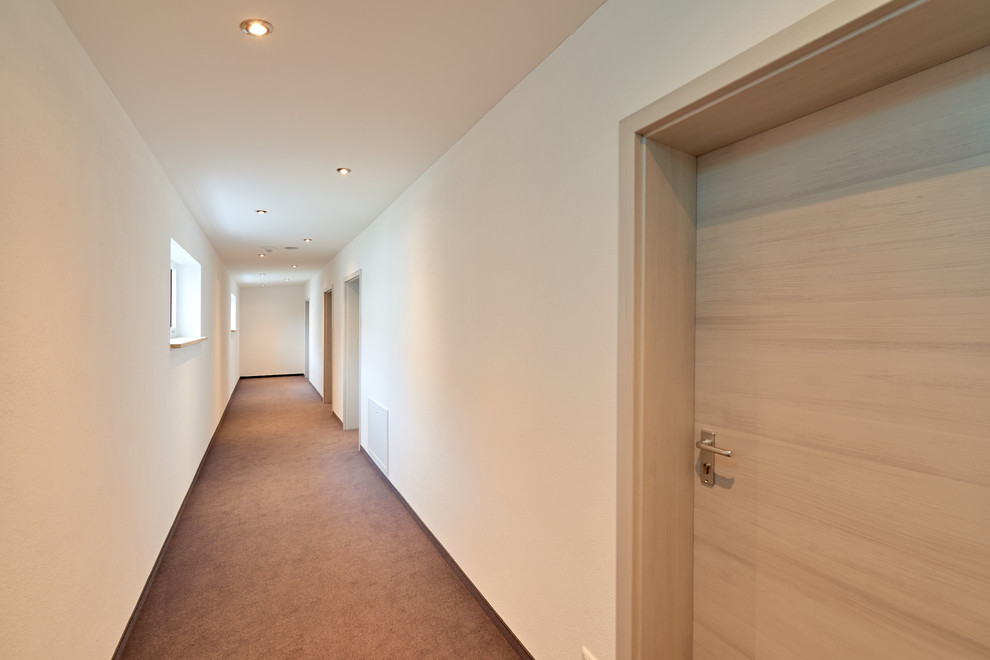 Пример оригинального дизайна: коридор среднего размера в стиле модернизм с белыми стенами, ковровым покрытием и коричневым полом