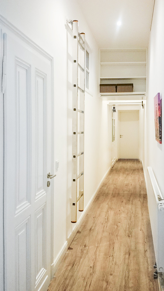 На фото: коридор среднего размера в современном стиле с белыми стенами, деревянным полом и коричневым полом
