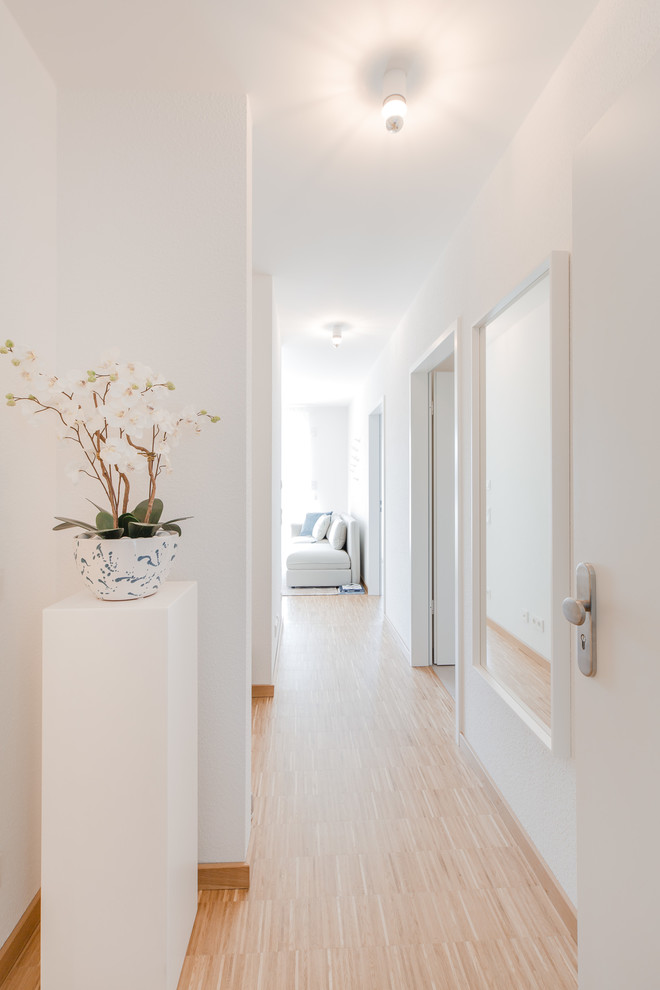 На фото: маленький коридор в скандинавском стиле с белыми стенами, полом из бамбука и бежевым полом для на участке и в саду