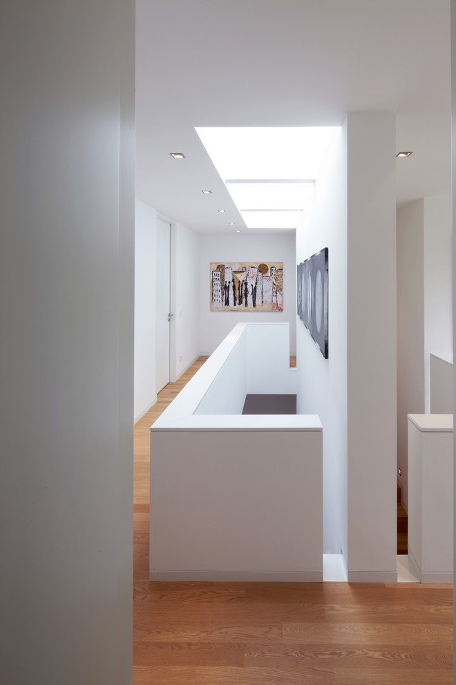 На фото: коридор среднего размера в современном стиле с белыми стенами, паркетным полом среднего тона и коричневым полом