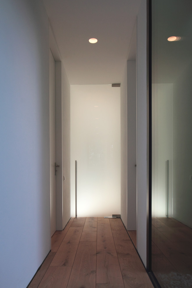 Inspiration pour un petit couloir minimaliste avec un mur blanc, un sol en bois brun et un sol marron.