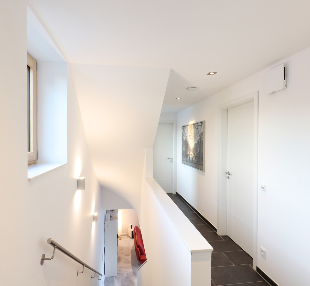 Ispirazione per un piccolo ingresso o corridoio moderno con pareti bianche e pavimento nero