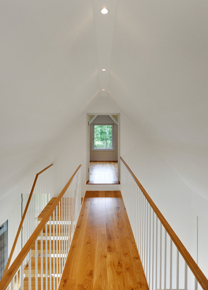 Idées déco pour un couloir contemporain de taille moyenne avec un mur blanc et un sol en bois brun.