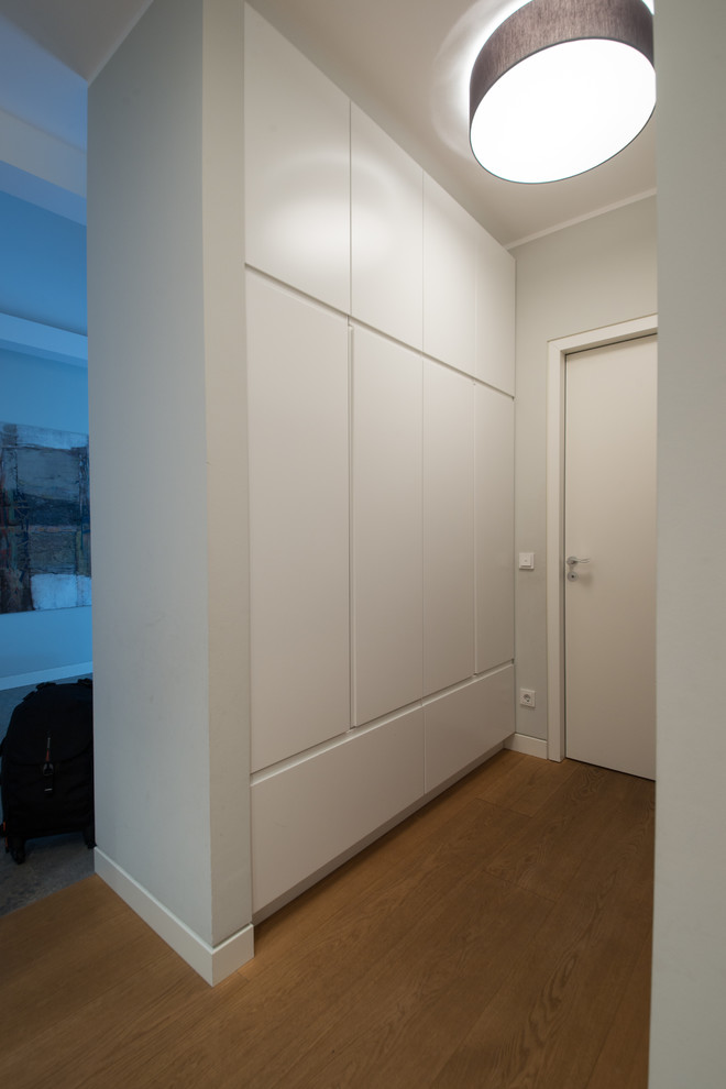 Kleiner Moderner Flur mit weißer Wandfarbe, braunem Holzboden und braunem Boden in Sonstige