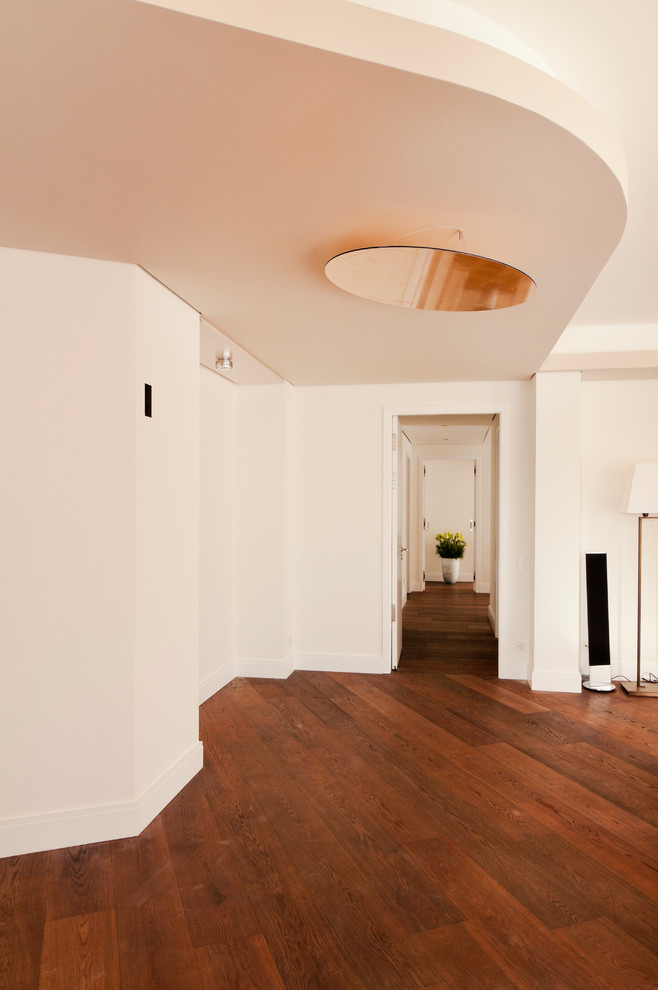 На фото: большой коридор в стиле модернизм с белыми стенами, темным паркетным полом и коричневым полом с