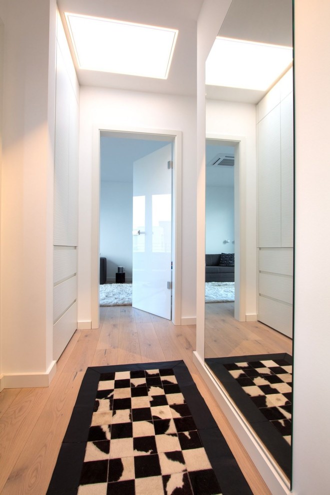 Ispirazione per un piccolo ingresso o corridoio moderno con pareti bianche, pavimento in legno massello medio e pavimento beige