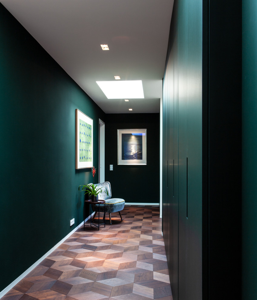 Cette image montre un grand couloir vintage avec un mur vert, un sol en bois brun, un sol marron et un plafond décaissé.
