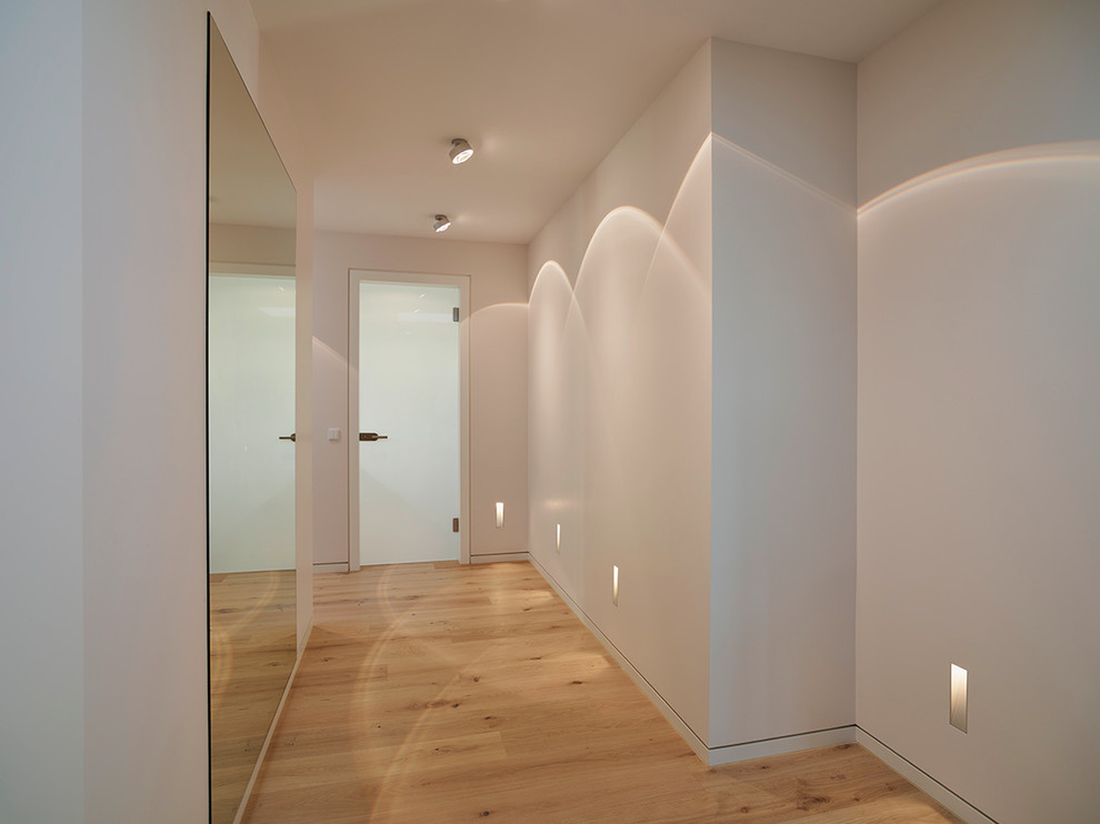 Idee per un ingresso o corridoio contemporaneo con pareti bianche e parquet chiaro