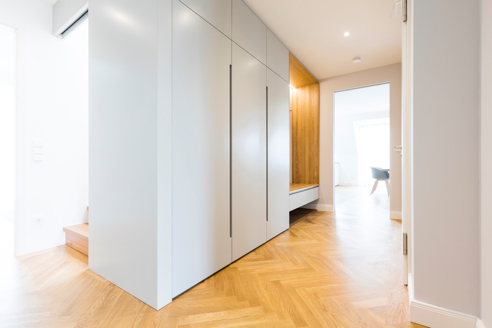 Стильный дизайн: коридор среднего размера в скандинавском стиле с серыми стенами, паркетным полом среднего тона и коричневым полом - последний тренд