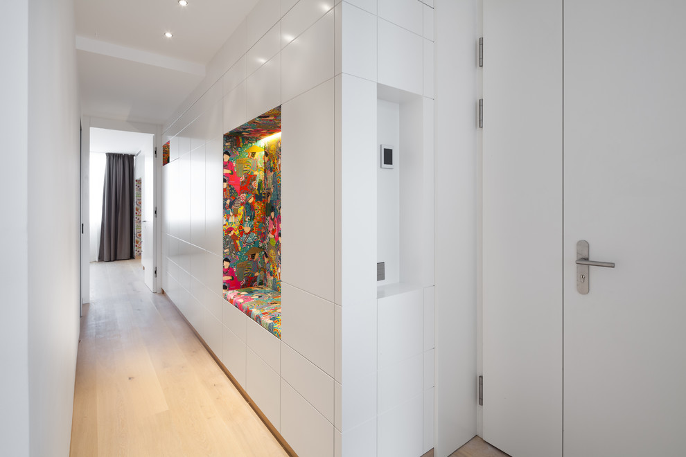 Imagen de recibidores y pasillos minimalistas con paredes blancas, suelo de madera clara y suelo beige