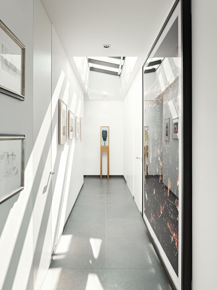 Cette photo montre un couloir tendance de taille moyenne avec un mur blanc et sol en béton ciré.