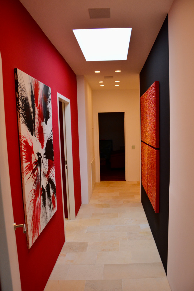 他の地域にあるラグジュアリーな中くらいなコンテンポラリースタイルのおしゃれな廊下 (赤い壁、ライムストーンの床、ベージュの床) の写真
