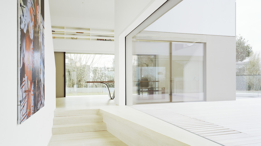 Foto di un grande ingresso o corridoio minimalista con pareti bianche e parquet chiaro