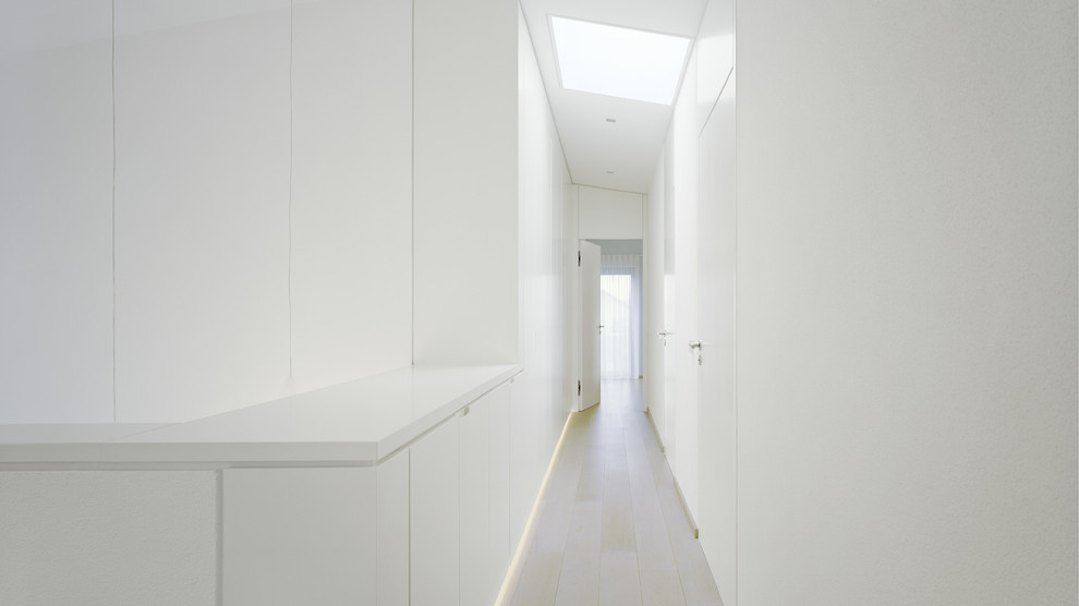 Immagine di un ingresso o corridoio design con pareti bianche e parquet chiaro