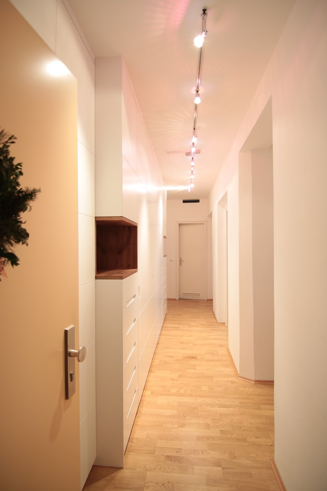 Réalisation d'un petit couloir design avec un mur blanc, parquet clair et un sol beige.