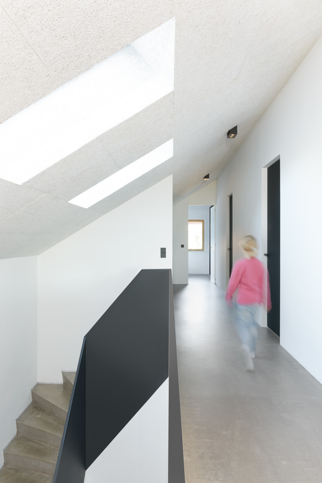 Modelo de recibidores y pasillos minimalistas de tamaño medio con paredes blancas, suelo de cemento y suelo gris