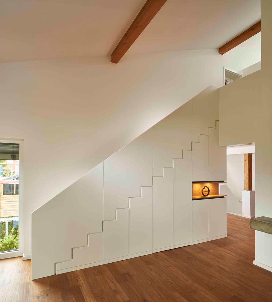 Foto di un ingresso o corridoio minimalista di medie dimensioni con pareti bianche, pavimento in legno massello medio e pavimento marrone