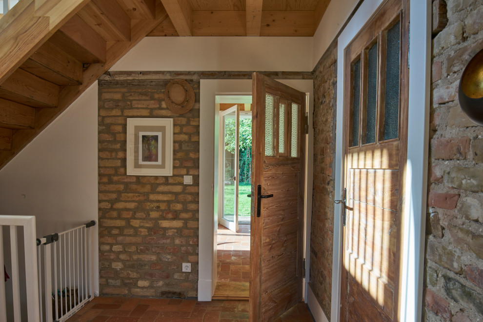 Diseño de recibidores y pasillos rurales grandes con paredes blancas, suelo de madera clara y suelo marrón