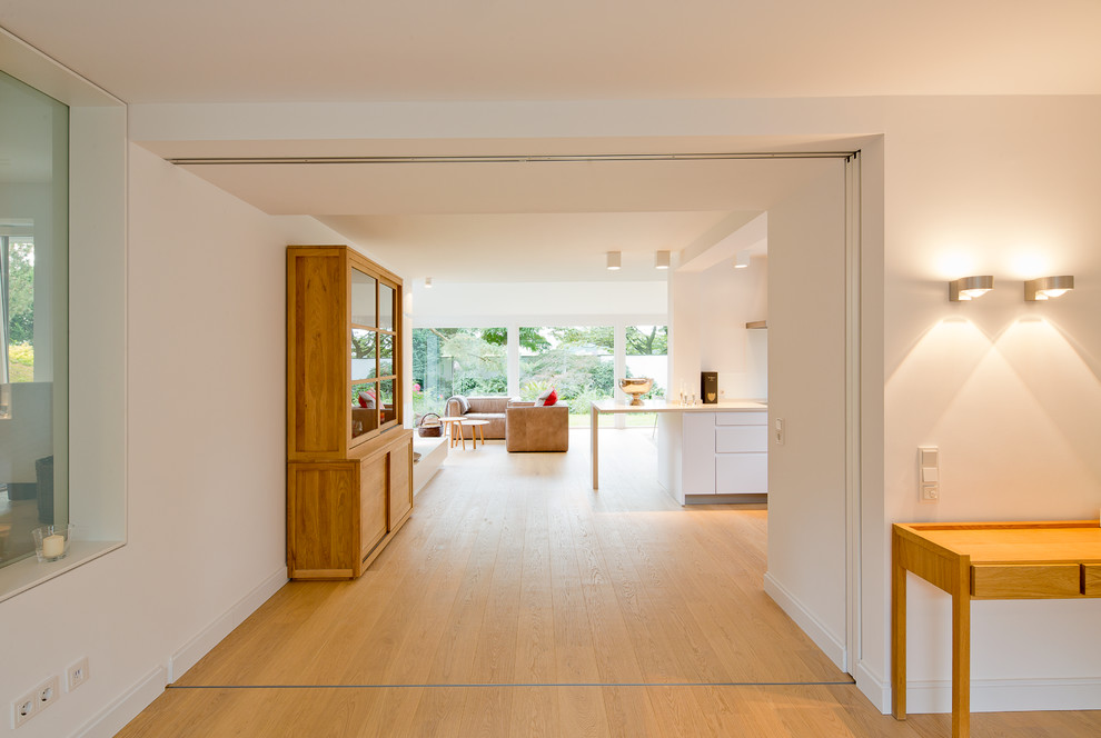 Cette image montre un grand couloir design avec un mur blanc et un sol en bois brun.