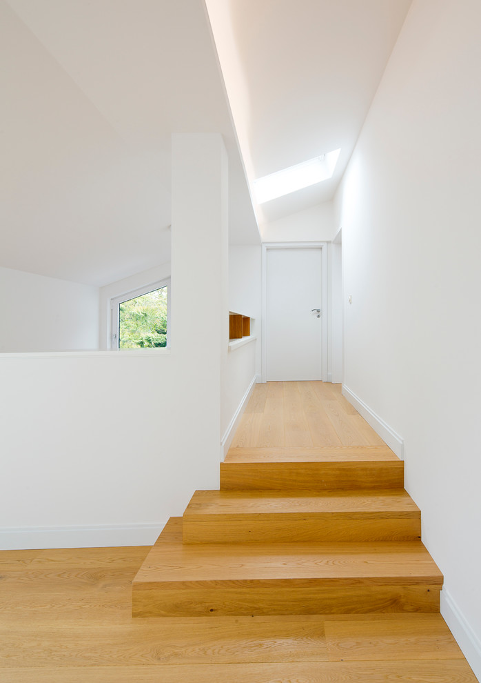 Diseño de recibidores y pasillos contemporáneos con paredes blancas y suelo de madera clara