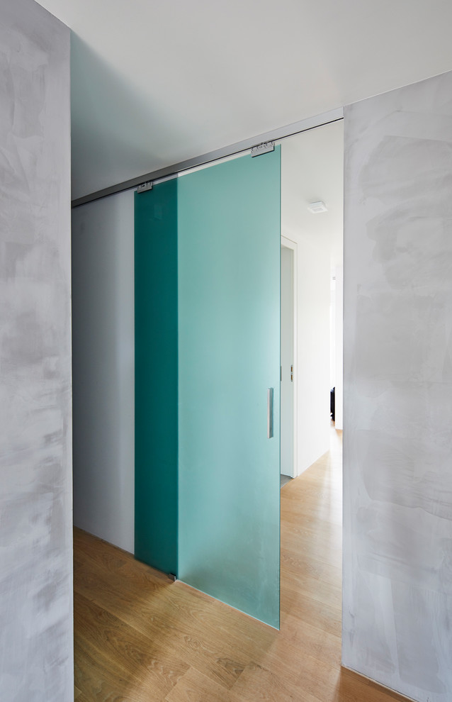 Ejemplo de recibidores y pasillos minimalistas de tamaño medio con paredes grises, suelo de madera en tonos medios y suelo marrón