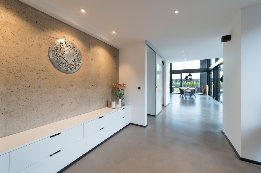 Стильный дизайн: большой коридор в стиле лофт с белыми стенами, бетонным полом и серым полом - последний тренд