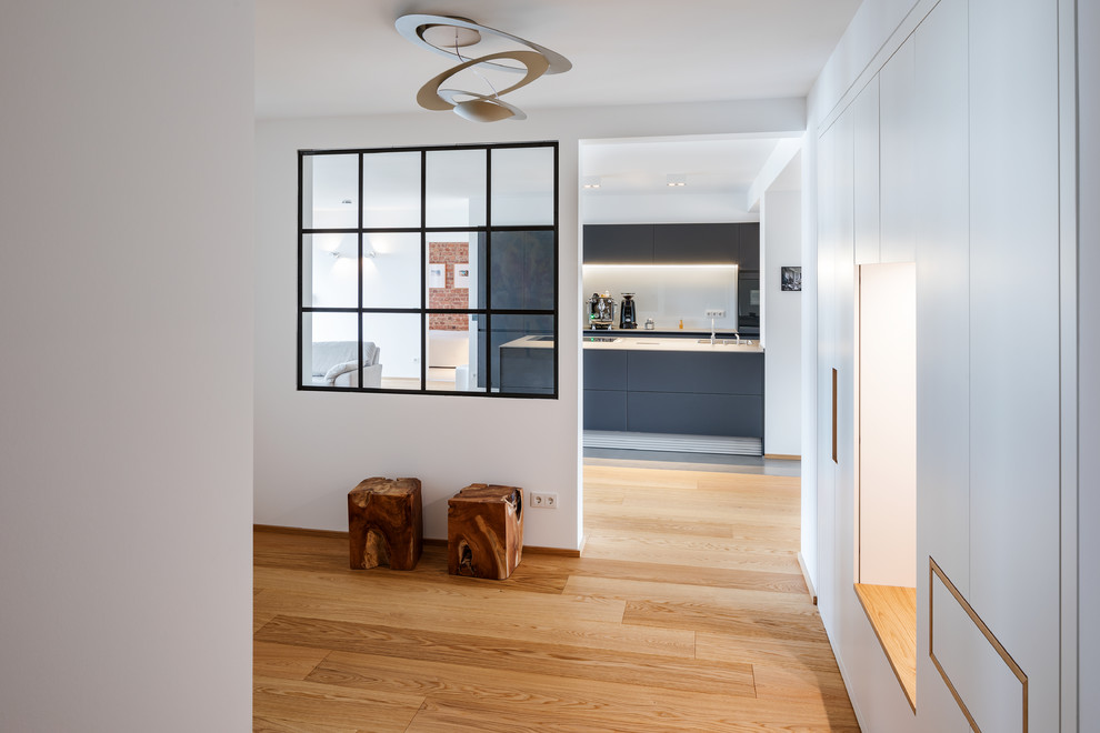 Inspiration for a large industrial medium tone wood floor and brown floor hallway remodel in Essen with white walls