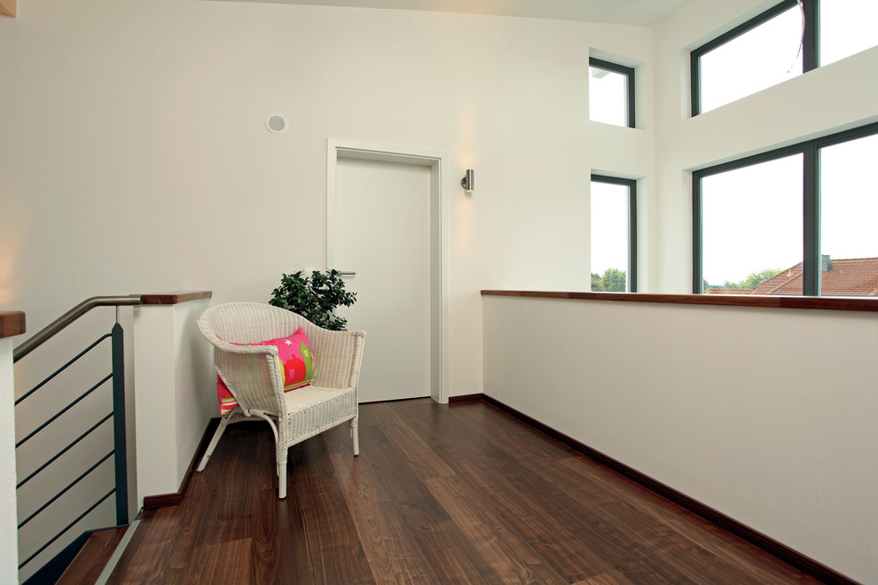 Moderner Flur mit weißer Wandfarbe, dunklem Holzboden und braunem Boden in Sonstige