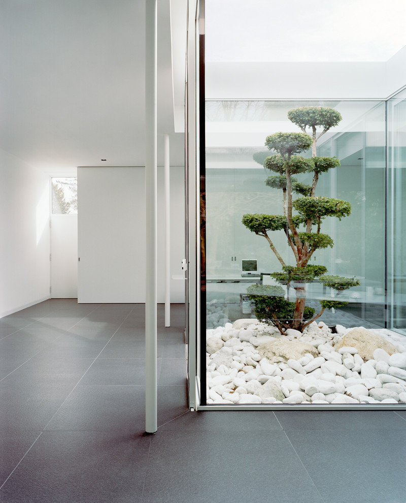 Cette image montre un grand couloir design avec un mur blanc et sol en béton ciré.