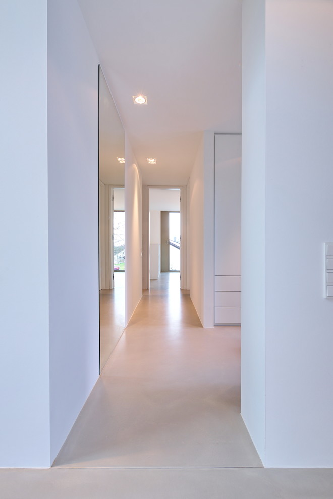 Ispirazione per un ampio ingresso o corridoio moderno con pareti bianche, pavimento in cemento e pavimento grigio