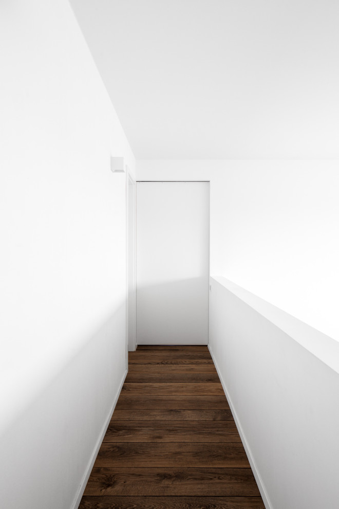 Imagen de recibidores y pasillos minimalistas de tamaño medio con paredes blancas, suelo de madera oscura y suelo marrón