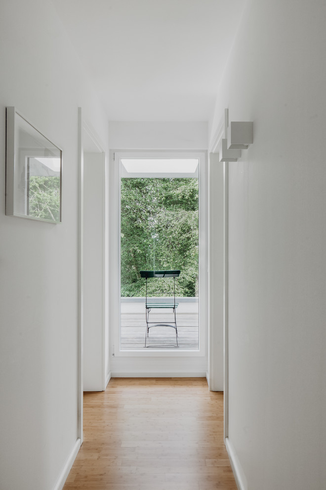 Mittelgroßer Moderner Flur mit weißer Wandfarbe, hellem Holzboden und braunem Boden in Frankfurt am Main